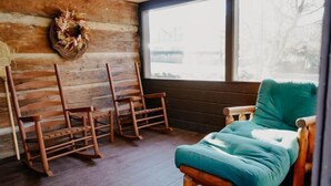 Un cuarto acogedor con paredes de madera, una mecedora, un sillón cómodo y una ventana con vistas.