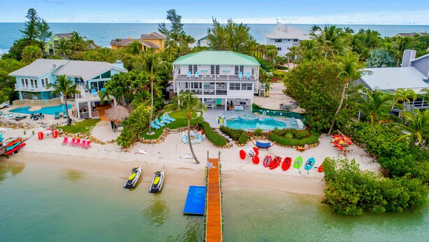 A beachfront property with a large house, a swimming pool, and a dock extending into the water. - Aquarius South: Luxe 10BR/6BA , w/ heated swimming pool+spa, private dock & more (Stuart)