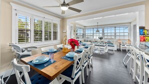 A spacious dining area with a wooden table set for six, white chairs, and a ceiling fan. - Aquarius South: Luxe 10BR/6BA , w/ heated swimming pool+spa, private dock & more (Stuart)