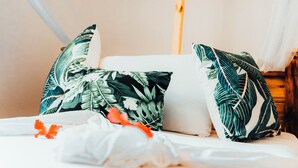 Un lit avec deux oreillers, une tête de lit en bois et un baldaquin blanc.