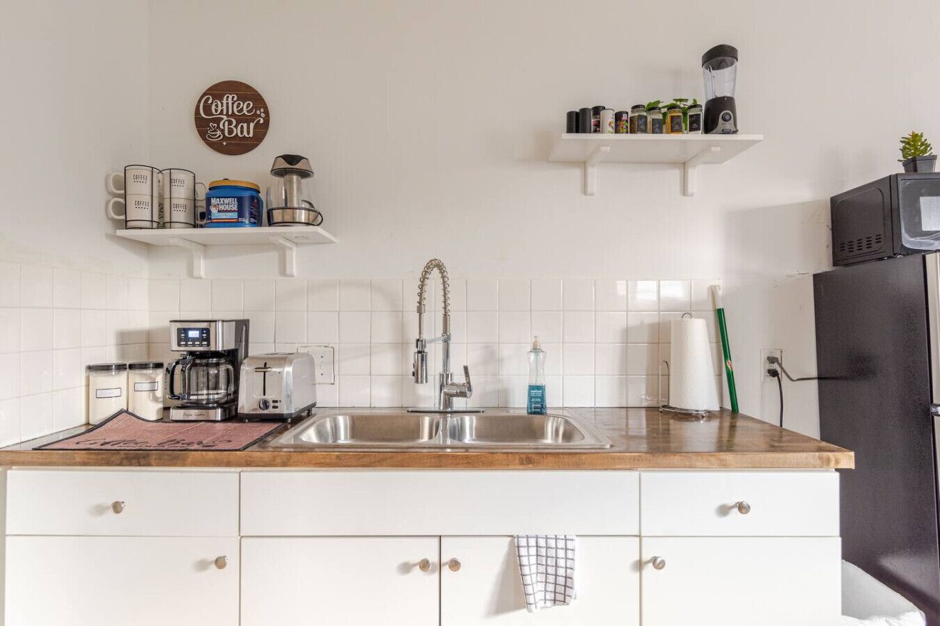 Een keuken met een koffiezetapparaat, broodrooster, gootsteen en een bordje 'Coffee & Bar'.