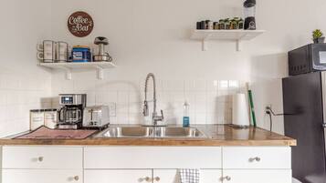 Een keuken met een koffiezetapparaat, broodrooster, gootsteen en een bordje 'Coffee & Bar'.