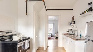 Une cuisine moderne avec un poêle noir, des armoires blanches et un plancher en bois.
