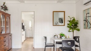 Un coin repas avec une table blanche, des chaises noires et un miroir au mur.