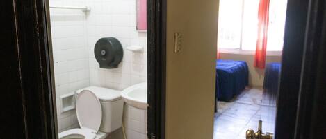 A bathroom with a toilet, sink, and a blue trash bin.