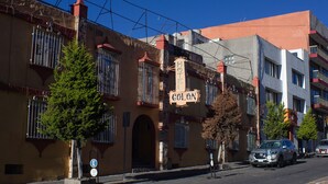 Hotel llamado "Hotel Colon", con un letrero, vista de la calle y coches estacionados.