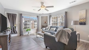Ein modernes Wohnzimmer mit grauem Sofa, einem Couchtisch und einem Deckenventilator.