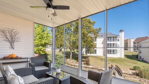 Eine überdachte Terrasse mit Korbmöbeln, einem Deckenventilator und Blick auf eine Wohngegend.