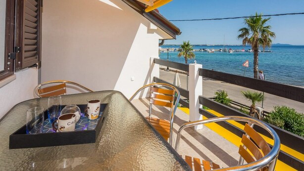 Un balcón con una mesa, sillas y vista al mar.