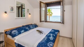 Un dormitorio con cama, ventana con vista al mar y una mesita.