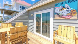 A wooden deck with outdoor furniture, a sliding glass door, and a mural on the wall. - Aint Dat A Beach Entire - 3BR Home on the 2nd Row (North Topsail Beach)