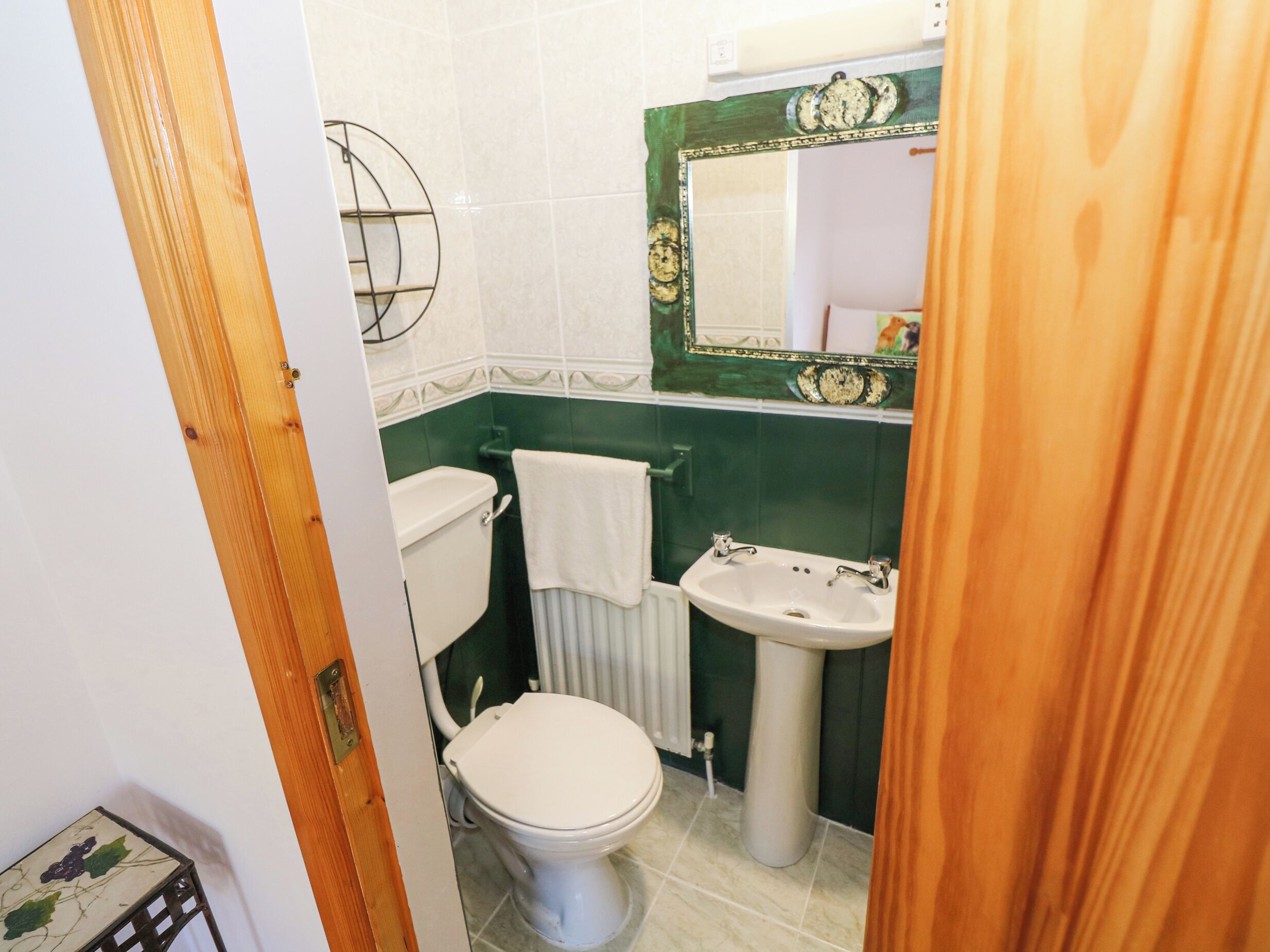 Casa de banho compacta com sanita, lavatório e espelho com moldura decorativa.