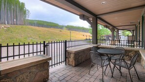 An outdoor patio with stone seating and a view of a forested hill. - True Ski-in/ski-out Luxury Condo On Peak 7 1 Bedroom Condo by RedAwning (Breckenridge)