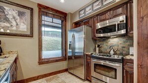 A kitchen with a stainless steel refrigerator, double ovens, a microwave, and a large window with a view of a grassy area. - True Ski-in/ski-out Luxury Condo On Peak 7 1 Bedroom Condo by RedAwning (Breckenridge)