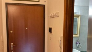 Una puerta de madera con un picaporte, un cuadro enmarcado encima y un baño visible a través de una puerta abierta.