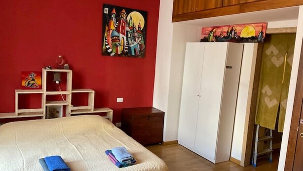 Un dormitorio con cama, armario, escritorio y un cuadro en la pared.