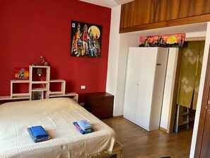 A bedroom with a bed, a wardrobe, a desk, and a painting on the wall. - IsoLaB: studio flat in the Isola area (Milano)