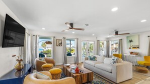 A spacious living room with a large sofa, a coffee table, and a TV mounted on the wall.