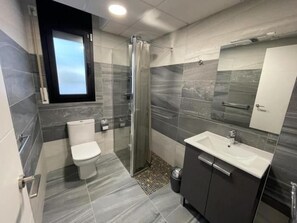 Un baño moderno con ducha, inodoro y lavamanos.