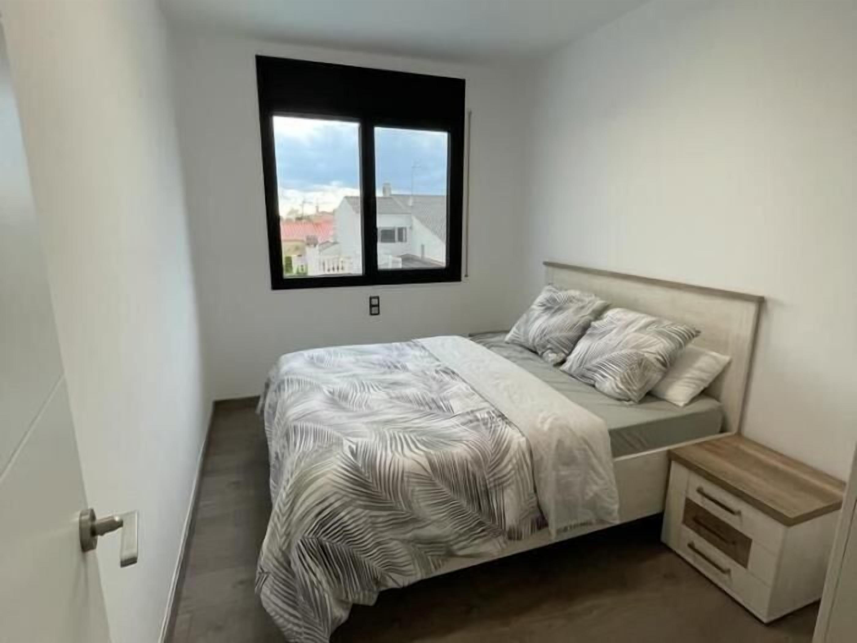 Ein Schlafzimmer mit einem Bett, einem Fenster und einem Nachttisch.