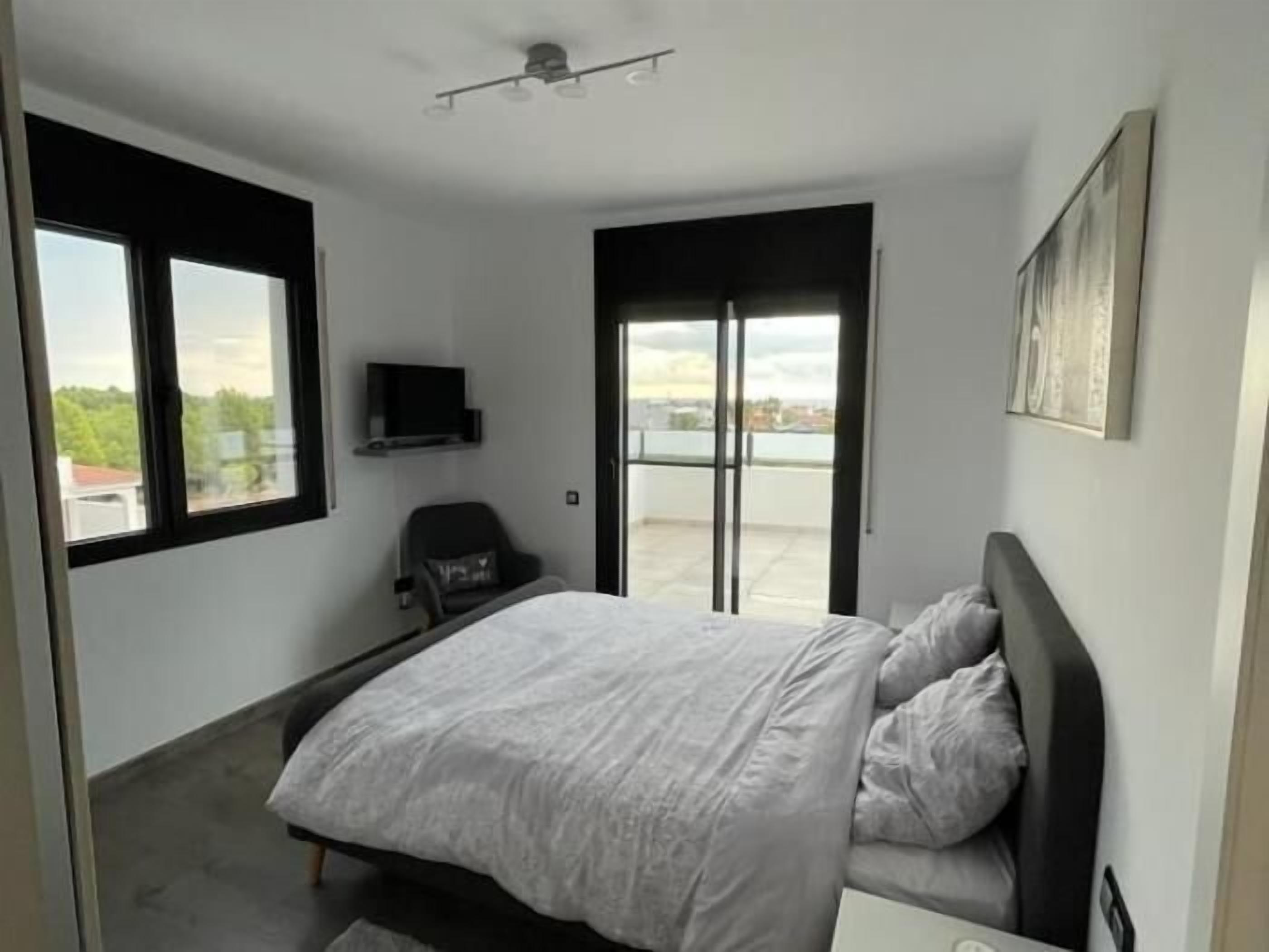 Ein Schlafzimmer mit Bett, Stuhl, Fernseher und Blick ins Freie.