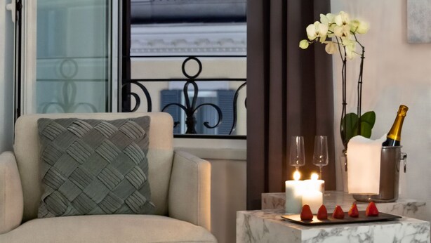 Una habitación moderna con sofá, una mesita de mármol con vela y vistas al exterior.
