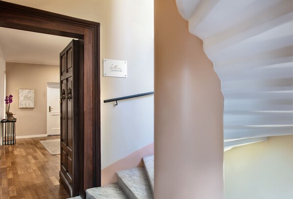 A staircase with a marble finish, a wooden door frame, and a sign on the wall. - Fellini Design Suites (Rome)