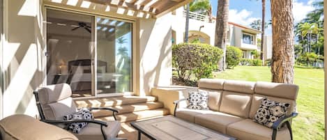 A covered outdoor seating area with a sofa, chairs, and a table.