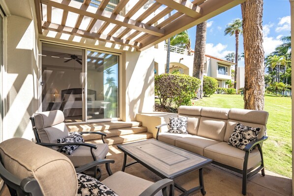 A covered outdoor seating area with a sofa, chairs, and a table.