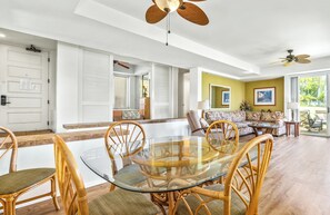 A spacious living area with a glass-top dining table surrounded by wicker chairs, a sofa, and a coffee table. - Palms at Wailea #1207 Ground Floor Unit, Near Complex Pool and Shared Hot Tub (Wailea)