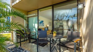 Une terrasse extérieure avec des meubles en osier, une table ronde et une plante en pot.