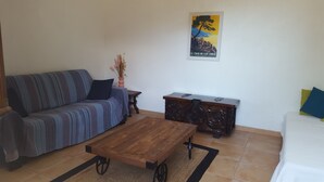 Een woonkamer met een bank, een salontafel, een houten kast en een poster aan de muur.