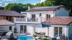 Ein zweistöckiges Haus mit Swimmingpool, Gartenmöbeln und einem gepflegten Garten.