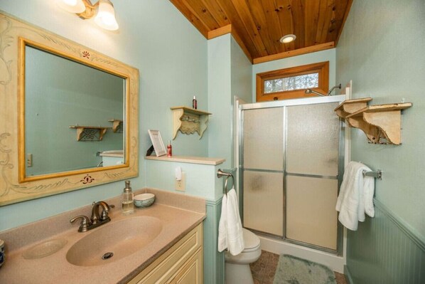 Een badkamer met een grote spiegel, een wastafel, een toilet en een douche.