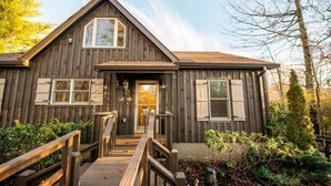 A wooden cabin with a front porch, a staircase, and a small garden area.