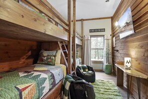 Una habitación acogedora de estilo cabaña con una litera, un escritorio con lámpara y un cartel que dice "NO ALIMENTAR A LOS OSOS".