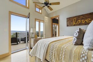 Un dormitorio con una cama grande, ventilador de techo y vistas al exterior.