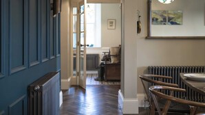 A hallway with a blue door, a radiator, and a dining area with a table and chairs. - The Old Vicarage,  Country Retreat by LetMeStay (Ambleside)