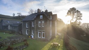 A stone house with a sloped roof, a chimney, and a small garden with a table and chairs. - The Old Vicarage,  Country Retreat by LetMeStay (Ambleside)