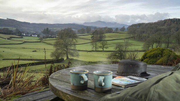 A picnic table with two mugs and a hat, overlooking a rural landscape with fields and trees. - The Old Vicarage,  Country Retreat by LetMeStay (Ambleside)