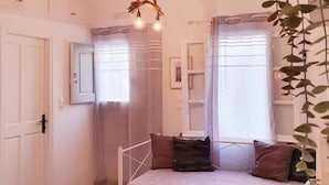 A cozy room with a bed, a small table, and a hanging light fixture. - Cute studio in downtown Mykonos (Mykonos)