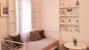 A cozy room with a bed, a round table, and shelves with decorative items. - Cute studio in downtown Mykonos (Mykonos)