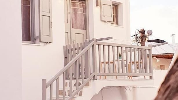 A two-story building with a balcony, a staircase, and a satellite dish. - Cute studio in downtown Mykonos (Mykonos)
