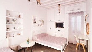 A bedroom with two beds, a desk, a TV, and a ceiling with exposed beams. - Cute studio in downtown Mykonos (Mykonos)