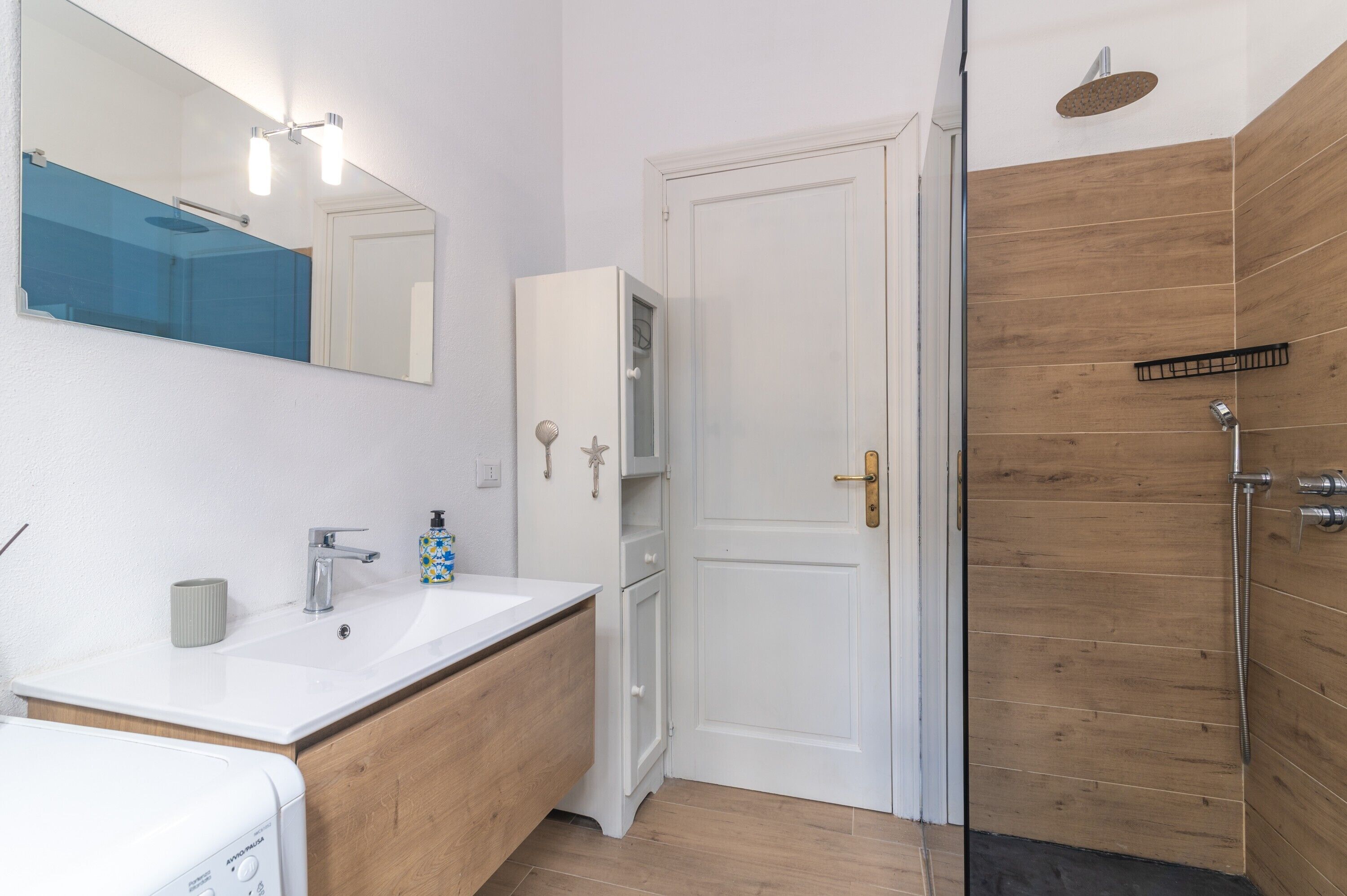 Ein Badezimmer mit Waschbecken, Spiegel, Schrank und Dusche.