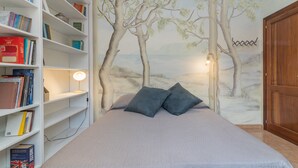 Une chambre à coucher avec un lit, une bibliothèque et une fresque murale.