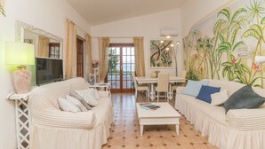 Un salon comprenant deux canapés, une table basse, un téléviseur et un coin repas avec une table et des chaises.