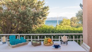 Un balcon avec une table préparée pour le thé, un panier de fruits et des objets décoratifs.