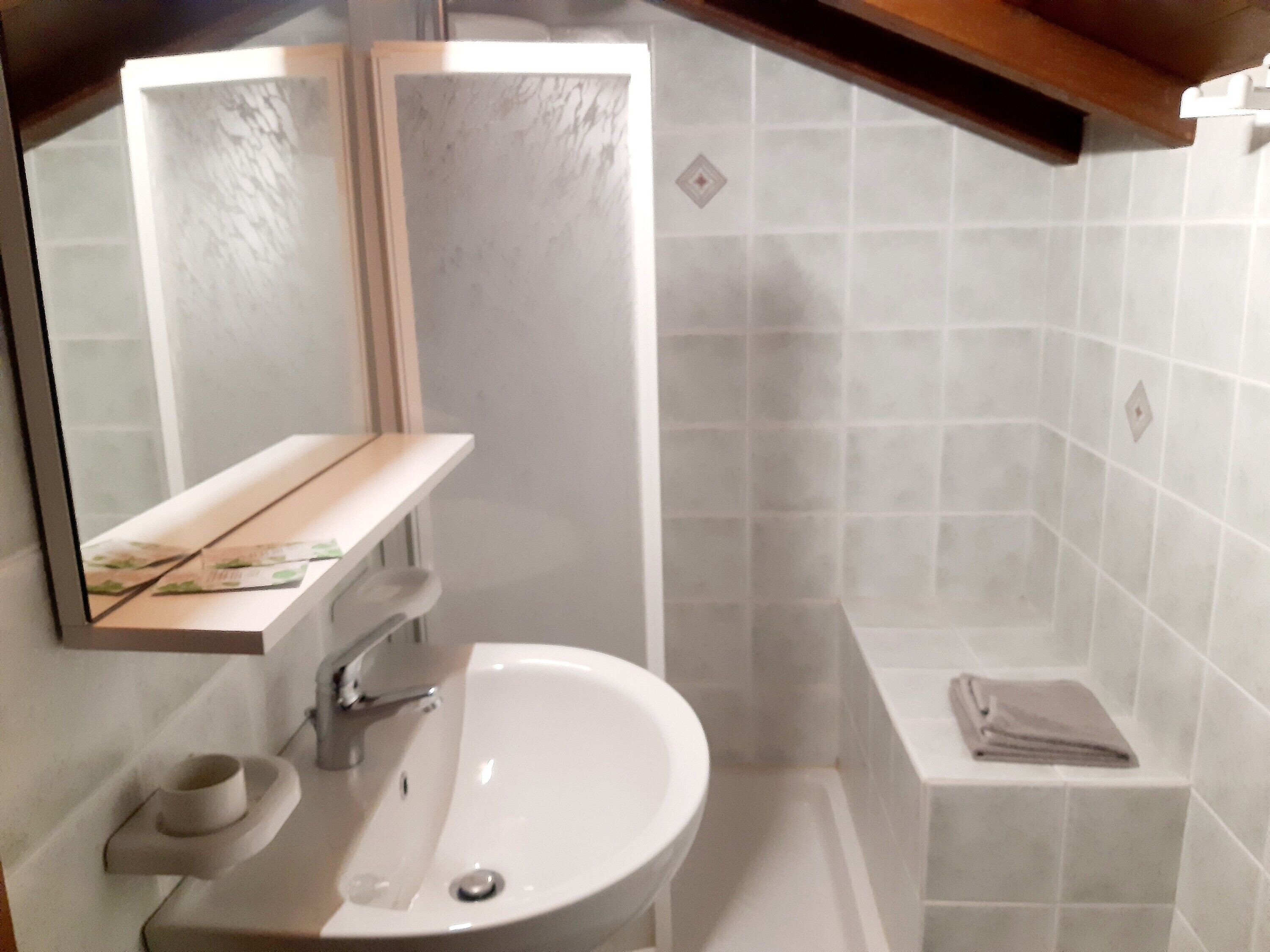 Un baño con lavamanos, espejo y perchero.