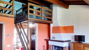 Ein Schlafzimmer im Loft-Stil mit einer Holztreppe, einem Kamin und einem Fernseher.
